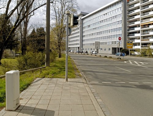 Der offizielle Fußweg am Cramer-Klett-Park endet an einer Fußgängerampel, die die Überquerung der entgegenkommenden 4-spurige Straße nach rechts ermöglicht. Im Gras geradeaus ist ein Trampelpfad sichtbar. 