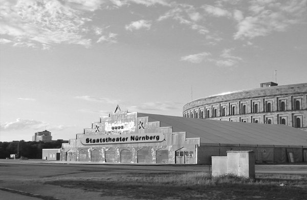 Ein einsames Festzelt auf dem Volksfestplatz, dahinter ist die Kongresshalle zu erkennen. Vorne auf dem Zelt ist ein Banner angebracht auf dem jemand mit Fotomontage geschrieben hat "Staatstheater Nürnberg""