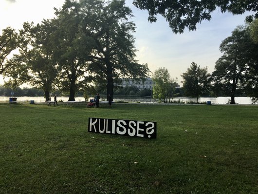 Foto: Kulisse? das steht auf einer Tafel, mitten auf der Spiegelwiese. Im Hintergrund der Dutzendteich und die Kongresshalle.