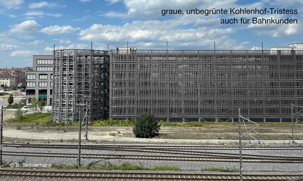 Blick auf das Parkhaus am Kohlenhof von der S-Bahn aus. Der graue Metall-Gitterbau verdeckt die dahinterliegenden Bürobauten. Das Parkhaus wirkt provisorisch und lieblos, die Fassade der Parketagen ist semi transparent, mit grauen Streifenblechen gestaltet, keine Begrünung.