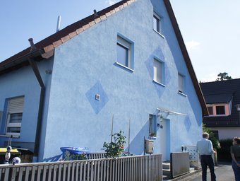Einfamilienhaus, ein zweistückiger Neubau, blau gestrichen, bis fast an die Grundstücksgrenze herangebaut.