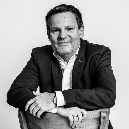 Portrait Florian Kluge, Mann im mittleren Alter, elegant gekleidet mit freundlichem aber ernstem Gesichtsausdruck 