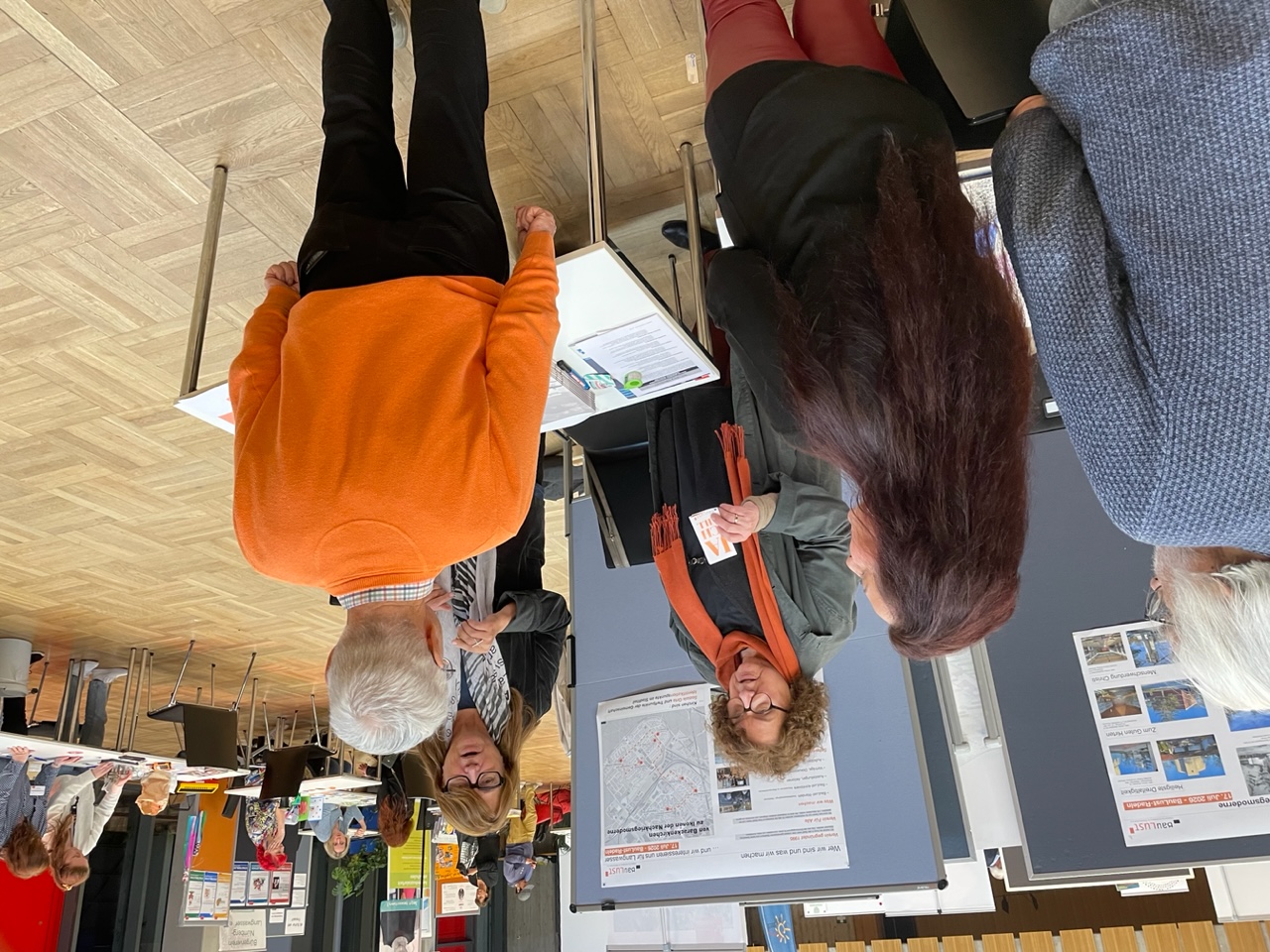 Brigitte Sesselmann und und Ulla Krämer hinterm Stand unterhalten sich angeregt drei Personen, die Atmosphäre ist freundlich und zugewandt.